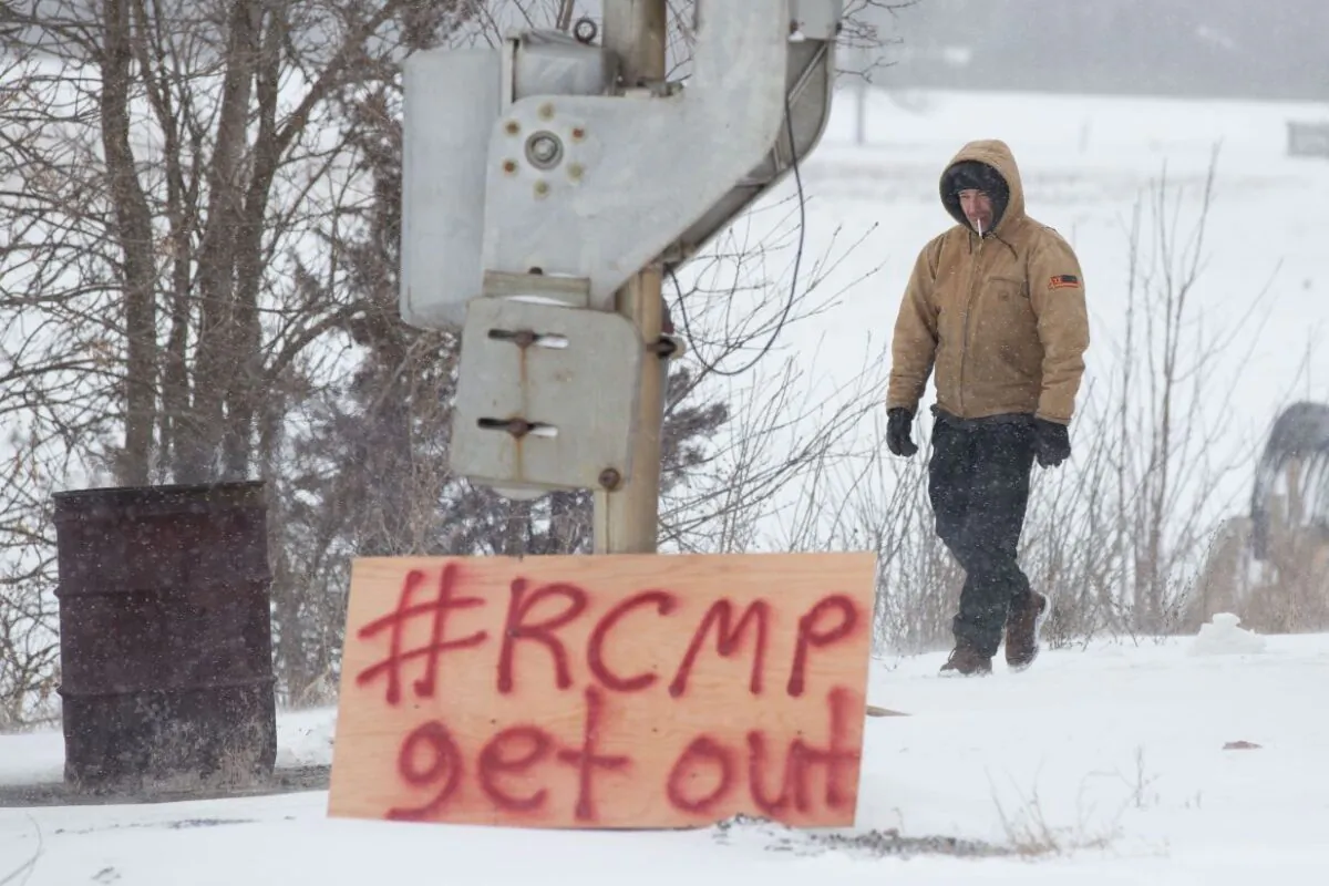A man walks past a sign put up by protesters blocking the CN tracks in Tyendinaga, Ont., on Feb.7, 2020, in support of the Wet'suwet'en members' blockade of a natural gas pipeline in northern B.C. (The Canadian Press/Lars Hagberg)