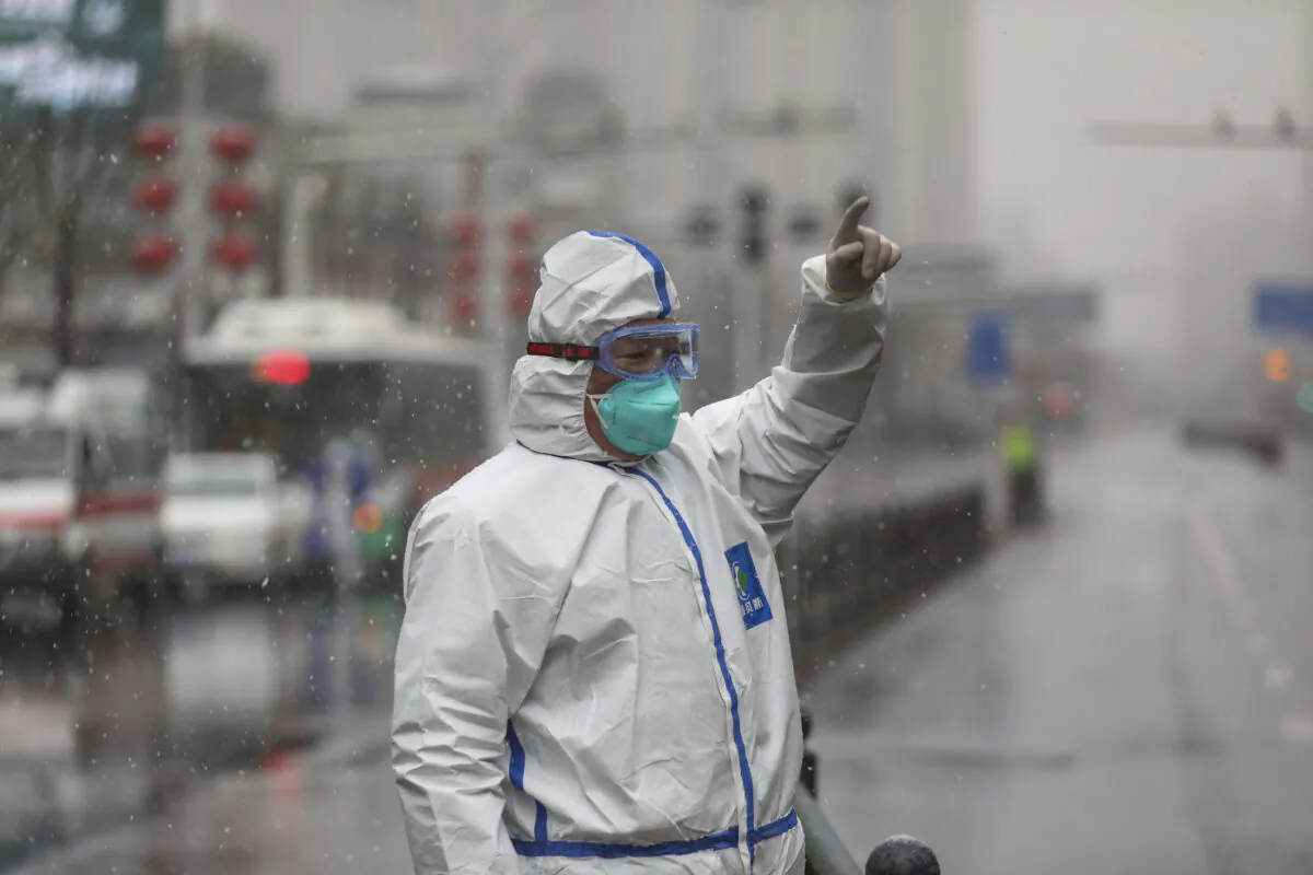 A worker wearing a protective suit gestures to a driver outside a tumor hospital newly designated to treat COVID-19 patients in Wuhan in central China's Hubei province on Feb. 15, 2020. (Chinatopix via AP)