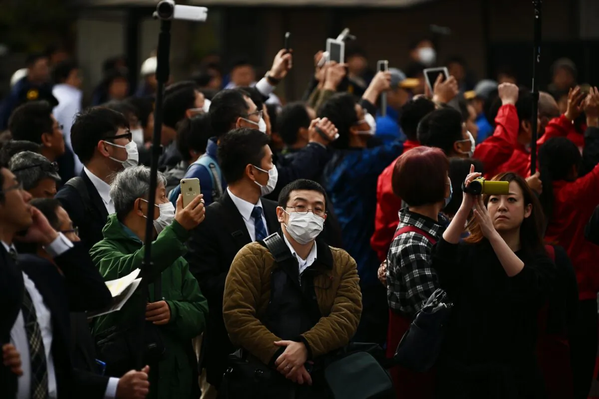 People wearing masks look on during a rehearsal of the Tokyo 2020 Olympics torch relay in Tokyo, Japan, on Feb. 15, 2020. (Charly Triballeau/AFP via Getty Images)