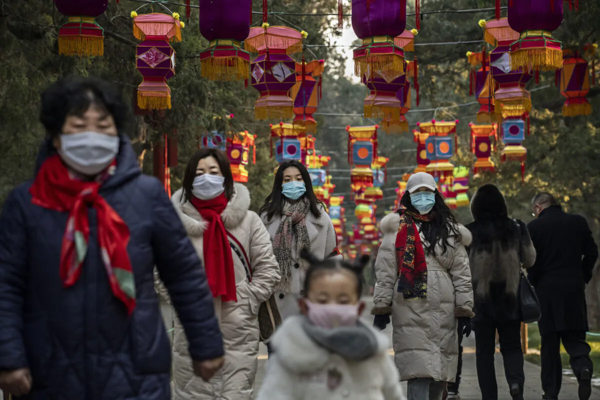 Residents wear protective masks as they walk under Chinese New Year decorations in a park in Beijing, China on Jan. 25, 2020. (Kevin Frayer/Getty Images)