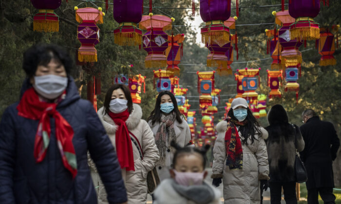 Residents wear protective masks as they walk under Chinese New Year decorations in a park in Beijing, China on Jan. 25, 2020. (Kevin Frayer/Getty Images)