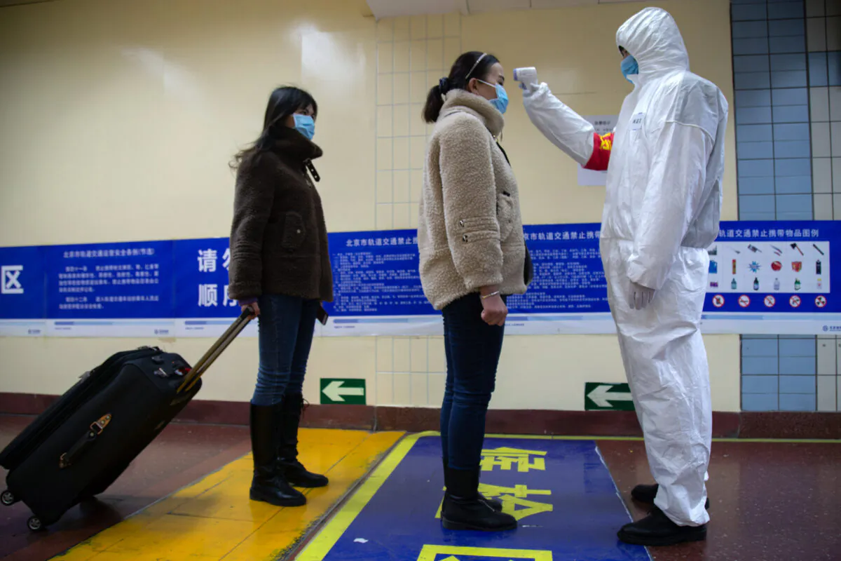 A health worker checks the temperature of women entering the subway, screening for possible coronavirus cases, in Beijing, China, on Jan. 26, 2020. (Betsy Joles/Getty Images)