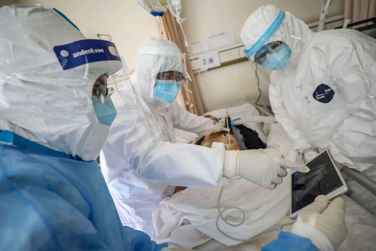 A doctor looking at an image as he checks a patient who is infected by the COVID-19 coronavirus at the Wuhan Red Cross Hospital in Wuhan in China's central Hubei province on Feb. 16, 2020. (STR/AFP via Getty Images)