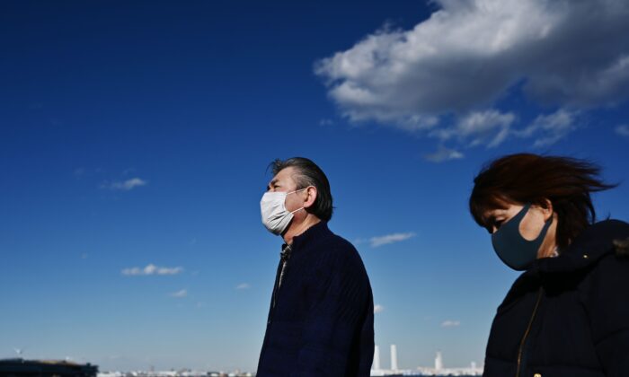People wearing face masks walk by the coast in Yokohama, Japan on Feb. 18, 2020. (Charly Triballeau/AFP via Getty Images)