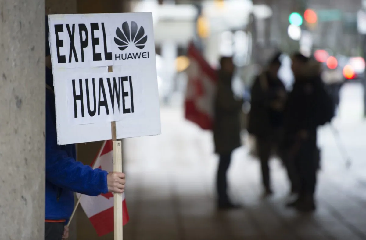 A man holds a sign outside the B.C. Supreme Court during Huawei executive Meng Wanzhou’s extradition hearing in Vancouver on Jan. 21, 2020. (The Canadian Press/Jonathan Hayward)