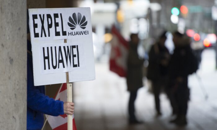 A man holds a sign outside the B.C. Supreme Court during Huawei executive Meng Wanzhou’s extradition hearing in Vancouver on Jan. 21, 2020. (The Canadian Press/Jonathan Hayward)