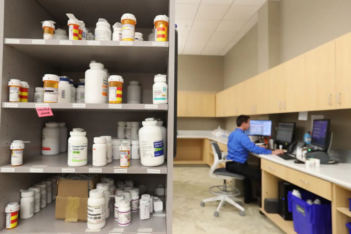 A pharmacy technician works on a computer as drug bottles sit on shelves at the central pharmacy of Intermountain Heathcare in Midvale, Utah, on Sept. 10, 2018. George Frey/Getty Images