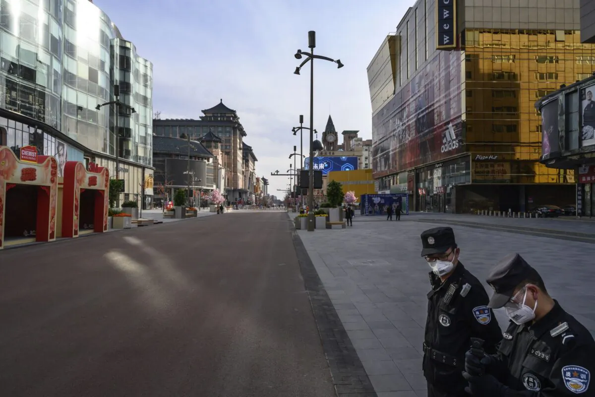Two Chinese security guards are guarding a nearly empty commercial street in one of the most busy neighborhoods Wangfujing in Beijing, China on Feb. 18, 2020. (Kevin Frayer/Getty Images)
