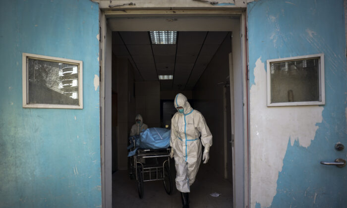 Medical workers move a person who died from COVID-19 at a hospital in Wuhan in central China's Hubei Province on Feb. 16, 2020. (Chinatopix via AP)