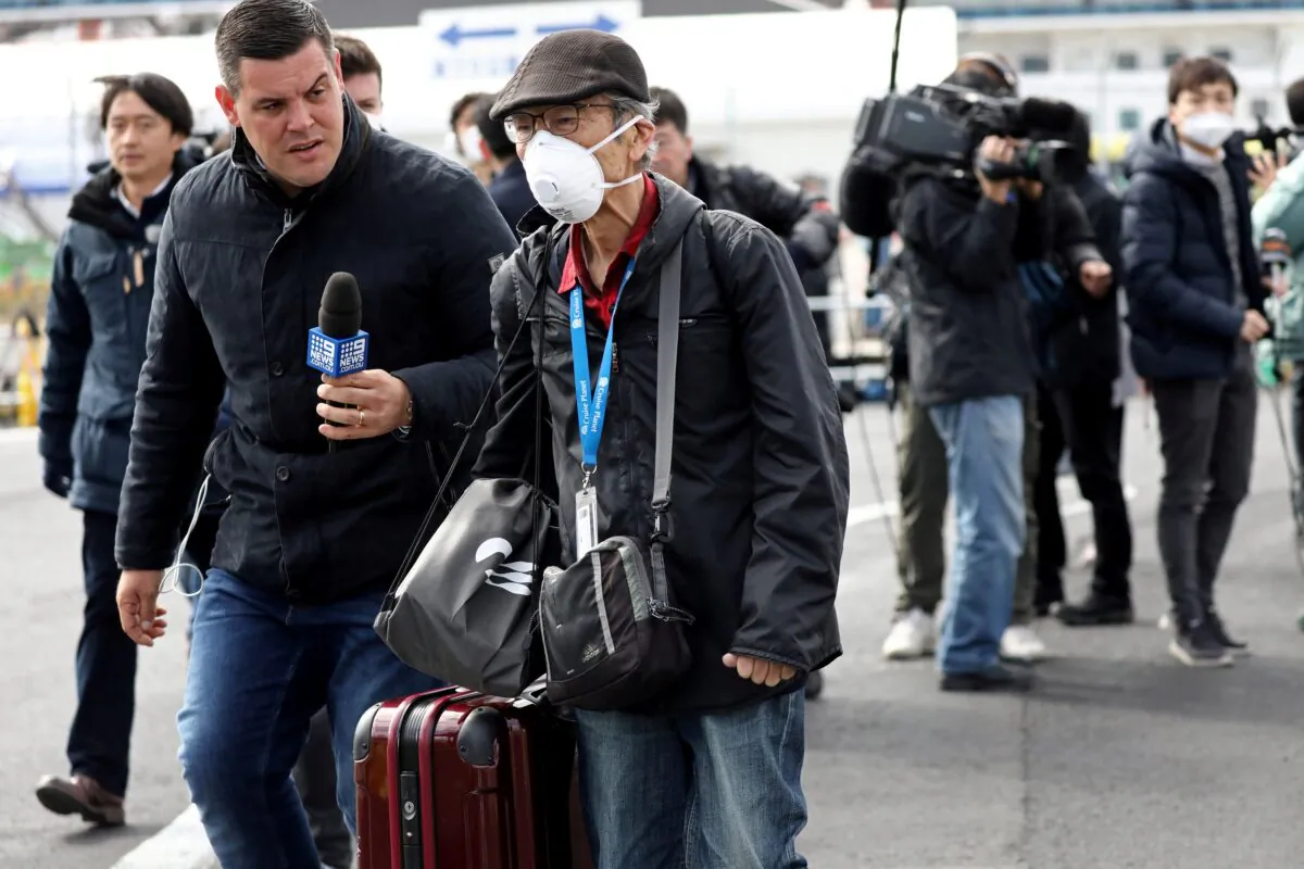A reporter approaches a passenger after he walked out from the cruise ship Diamond Princess at Daikoku Pier Cruise Terminal in Yokohama, south of Tokyo, Japan, on Feb. 19, 2020. (Athit Perawongmetha/Reuters)