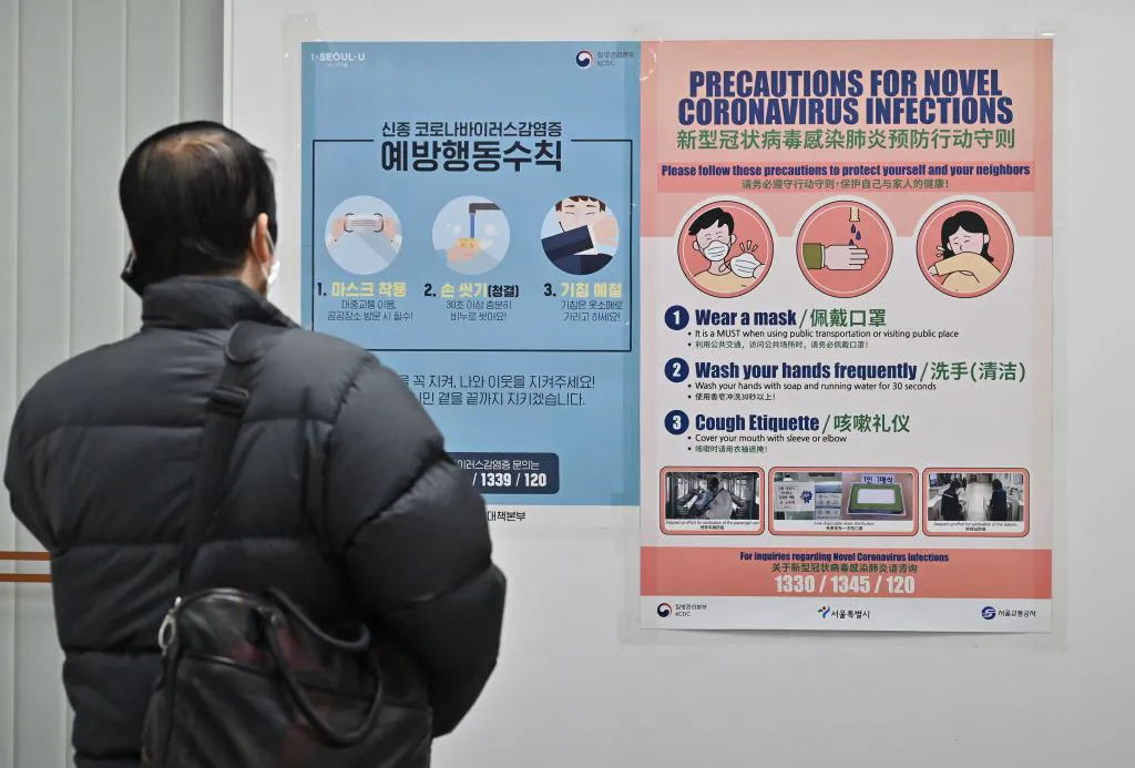 A man wearing a face mask talks on his mobile phone in front of a poster about precautions against the novel coronavirus that originated in central China, at a subway station in Seoul on Feb. 10, 2020. (Jung Yeon-je/AFP via Getty Images)