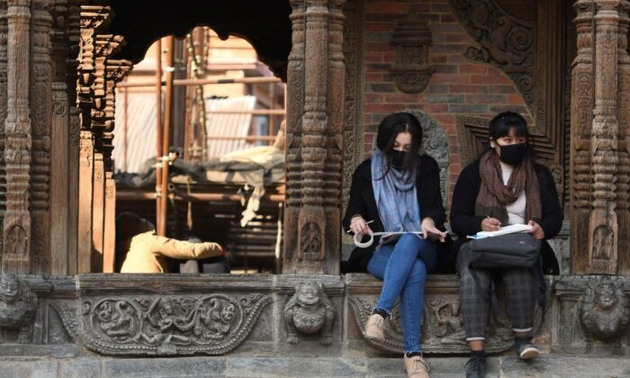 Residents wearing protective facemasks sit at Patan Durbar Square in Kathmandu, Nepal, on Feb. 10, 2020. (Prakash Mathema/AFP via Getty Images)
