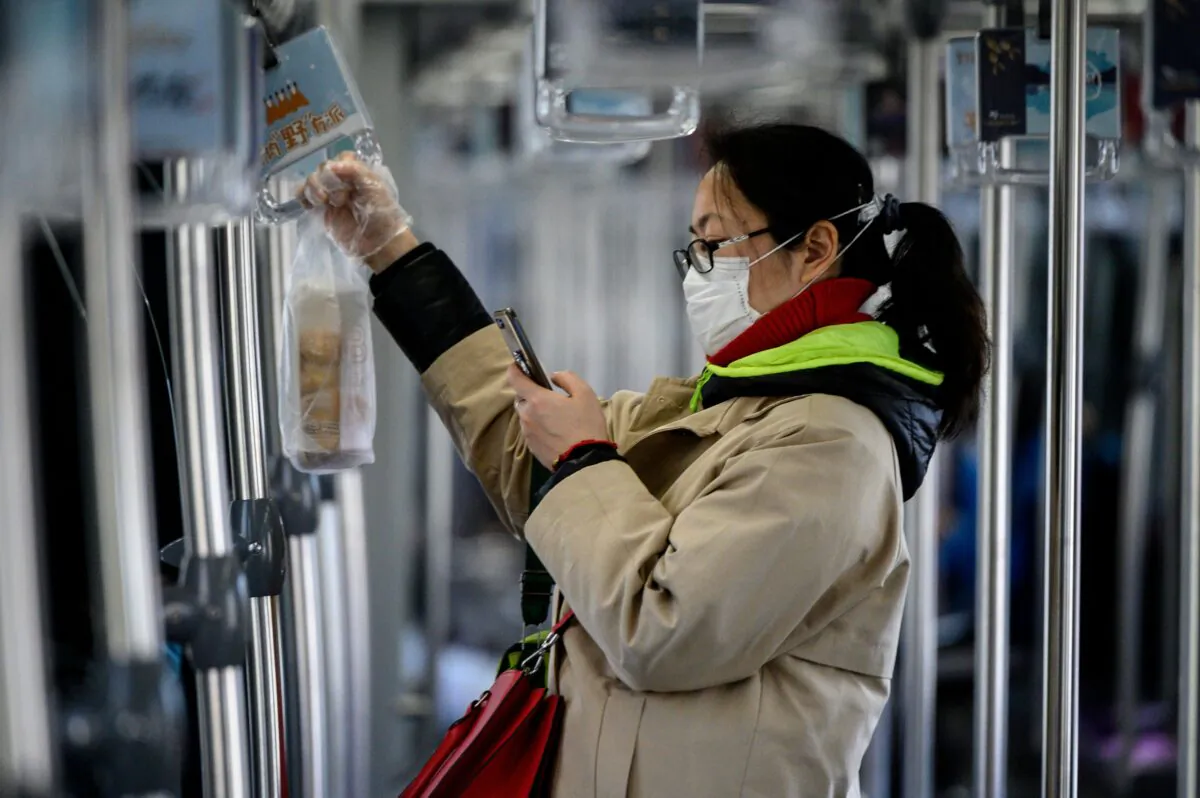 A woman wearing a protective facemask uses her mobile phone while riding a train in Shanghai on Feb. 20, 2020. (Noel Celis/AFP via Getty Images)
