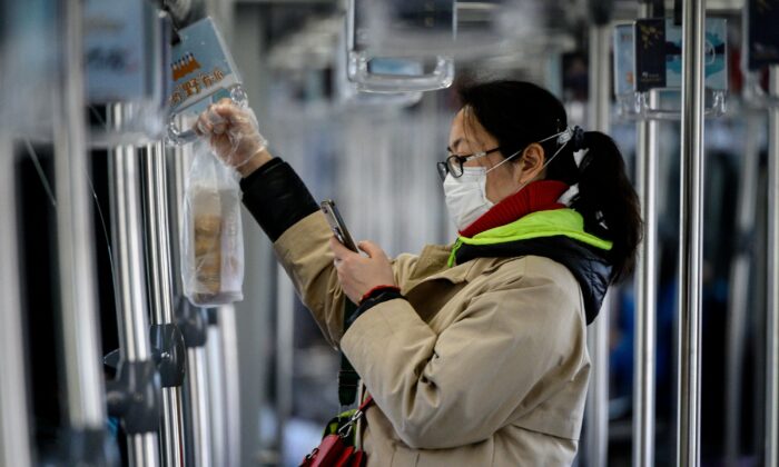 A woman wearing a protective facemask uses her mobile phone while riding a train in Shanghai on Feb. 20, 2020. (Noel Celis/AFP via Getty Images)