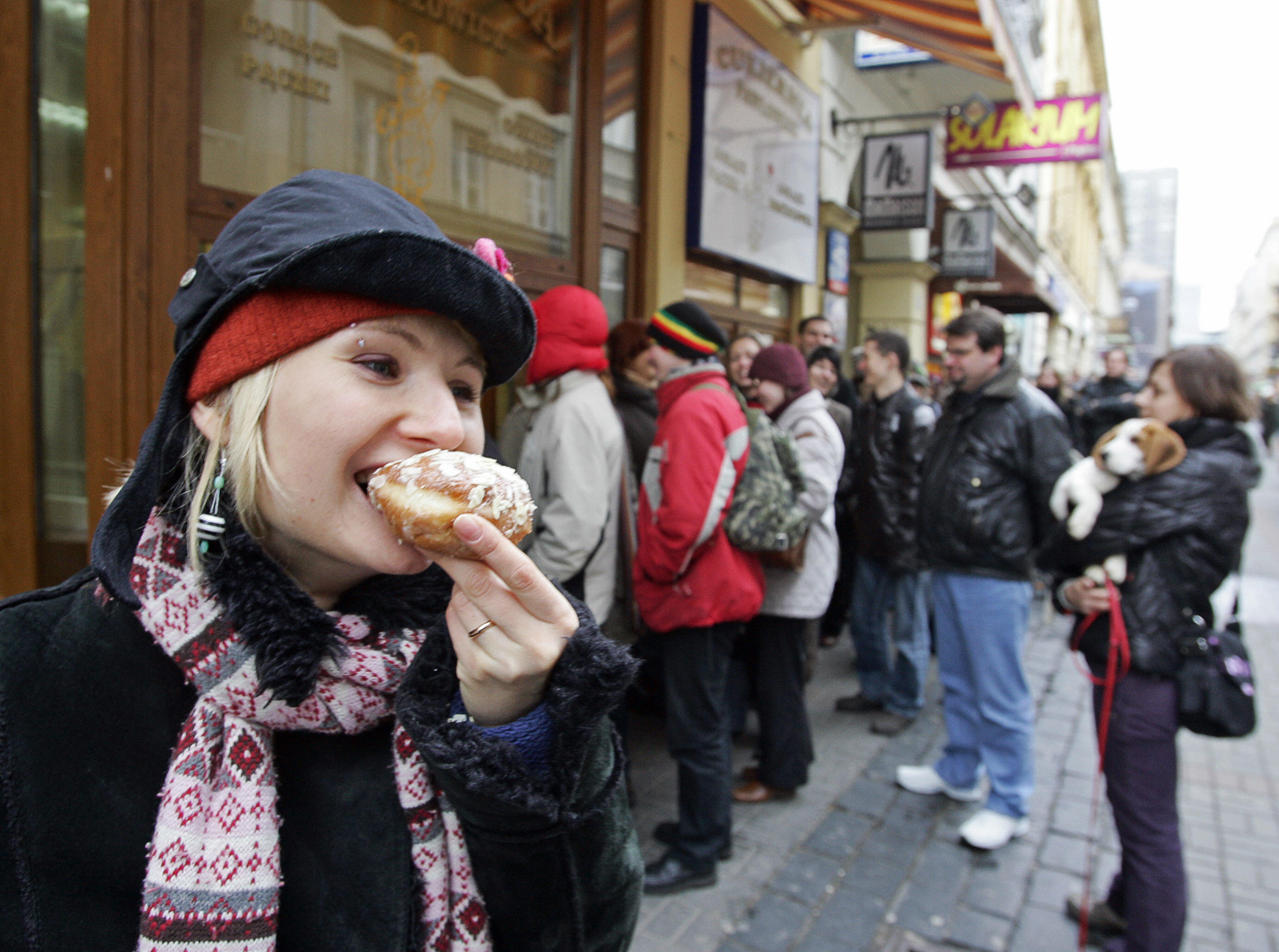 A girl eats a doughnut as other customer