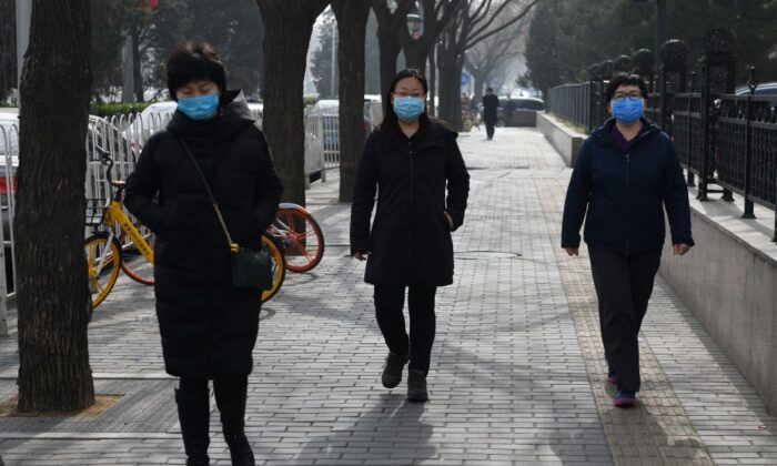 Women wear face masks as they walk on a street in Beijing on Feb. 21, 2020. (Greg Baker/AFP via Getty Images)