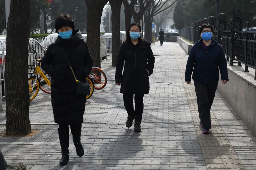 Women wear face masks as they walk on a street in Beijing on Feb. 21, 2020. (Greg Baker/AFP via Getty Images)