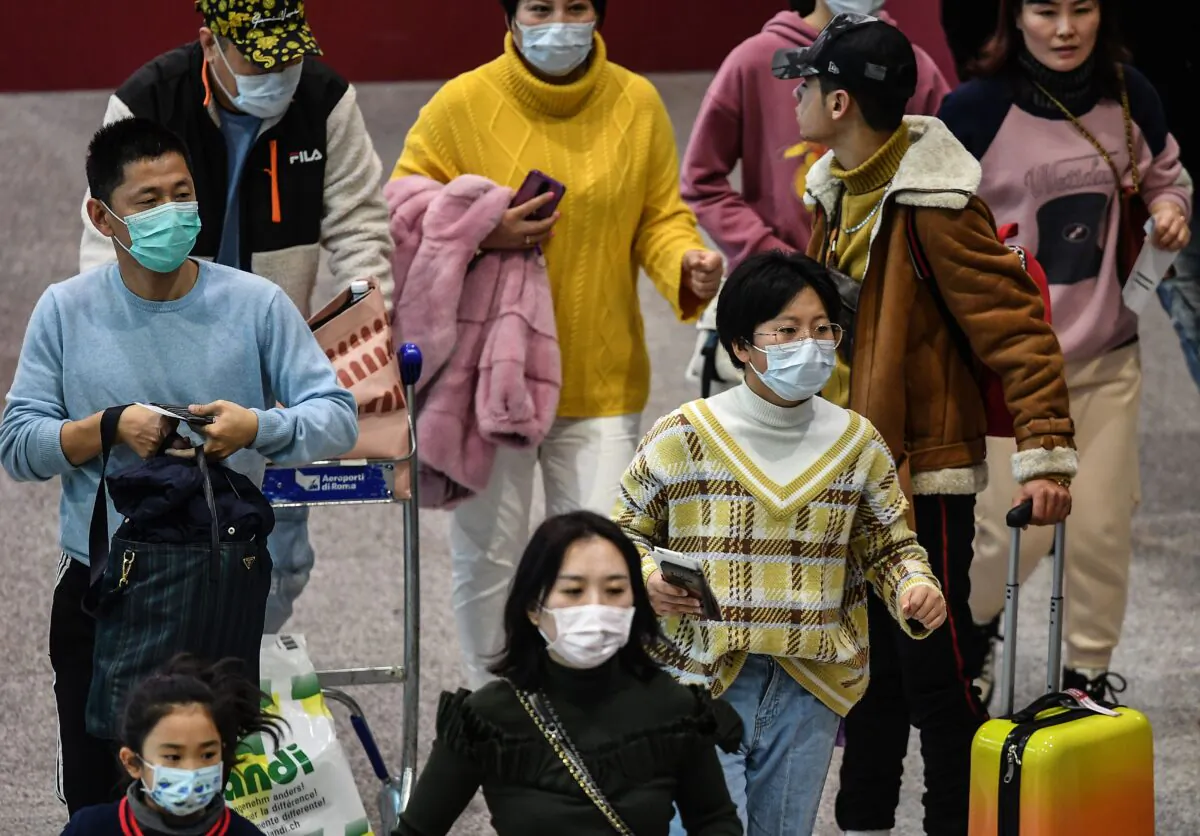 Passengers wearing respiratory masks walk across a terminal towards the check in counter at Rome's airport in Italy on Jan. 31, 2020. (Tiziana Fabi/AFP via Getty Images)