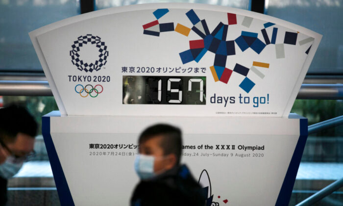 People wearing masks sit in front of a countdown clock for the Tokyo 2020 Olympics in Tokyo, on Feb. 18, 2020. (Jae C. Hong/AP Photo, File) 