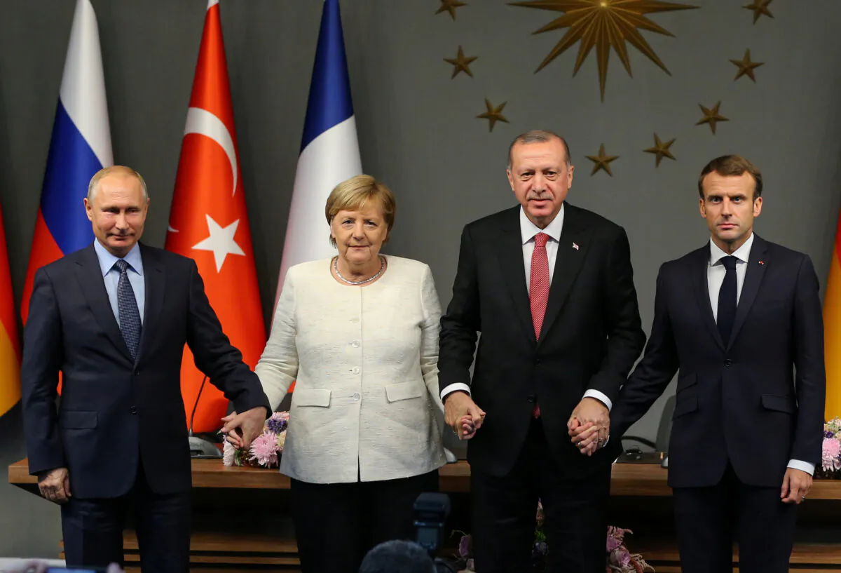 From left to right: Russian President Vladimir Putin, German Chancellor Angela Merkel, Turkish President Tayyip Erdogan, and French President Emmanuel Macron hold hands at a news conference after a Syria summit in Istanbul, Turkey, on Oct. 27, 2018. (Emrah Yorulmaz/Pool via REUTERS)