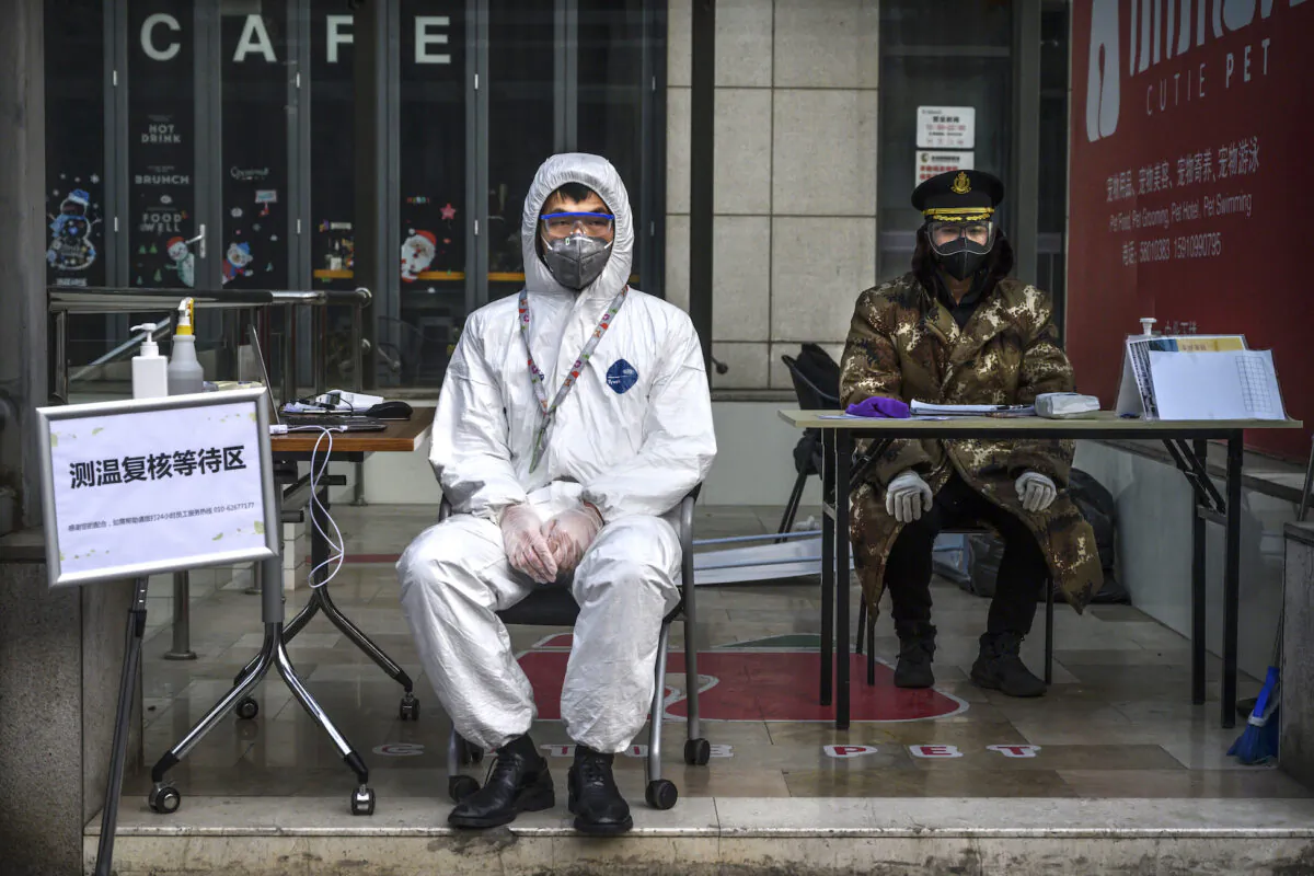 A Chinese guard wears a protective mask and suit as he waits to check temperatures and register people entering a building in a commercial area in Beijing on on Feb. 21, 2020. (Kevin Frayer/Getty Images)