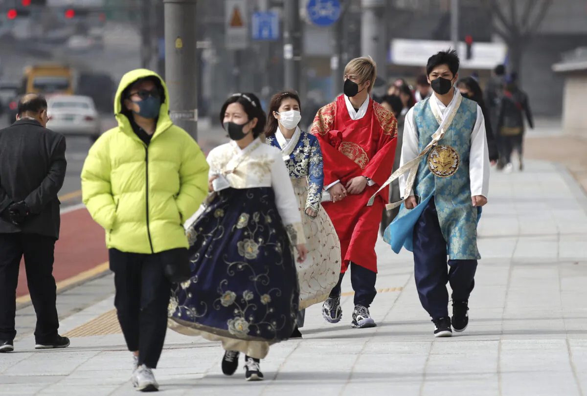 Visitors wearing face masks walk near the Gwanghwamun, the main gate of the 14th-century Gyeongbok Palace, and one of South Korea's well-known landmarks, in Seoul on Feb. 22, 2020. (Lee Jin-man/AP Photo)