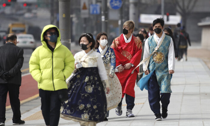 Visitors wearing face masks walk near the Gwanghwamun, the main gate of the 14th-century Gyeongbok Palace, and one of South Korea's well-known landmarks, in Seoul on Feb. 22, 2020. (Lee Jin-man/AP Photo)