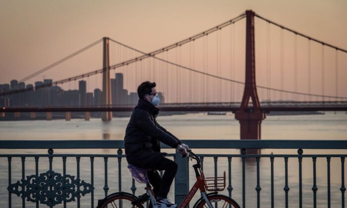 A man wearing a protective face mask rides a bicycle in Wuhan, China, on Feb. 17, 2020. (STR/AFP via Getty Images)