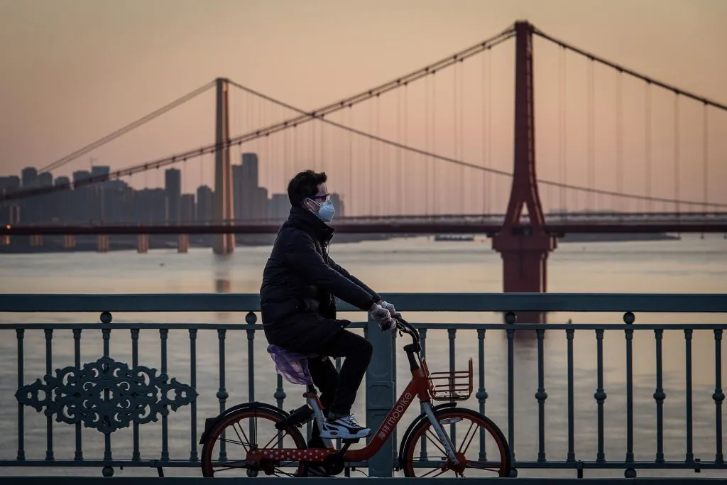 A man wearing a protective face mask rides a bicycle in Wuhan, China, on Feb. 17, 2020. (STR/AFP via Getty Images)