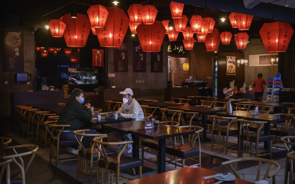 Two Chinese men sit in a nearly empty restaurant in the food court of a usually busy shopping mall in Beijing on Feb. 22, 2020. (Kevin Frayer/Getty Images)