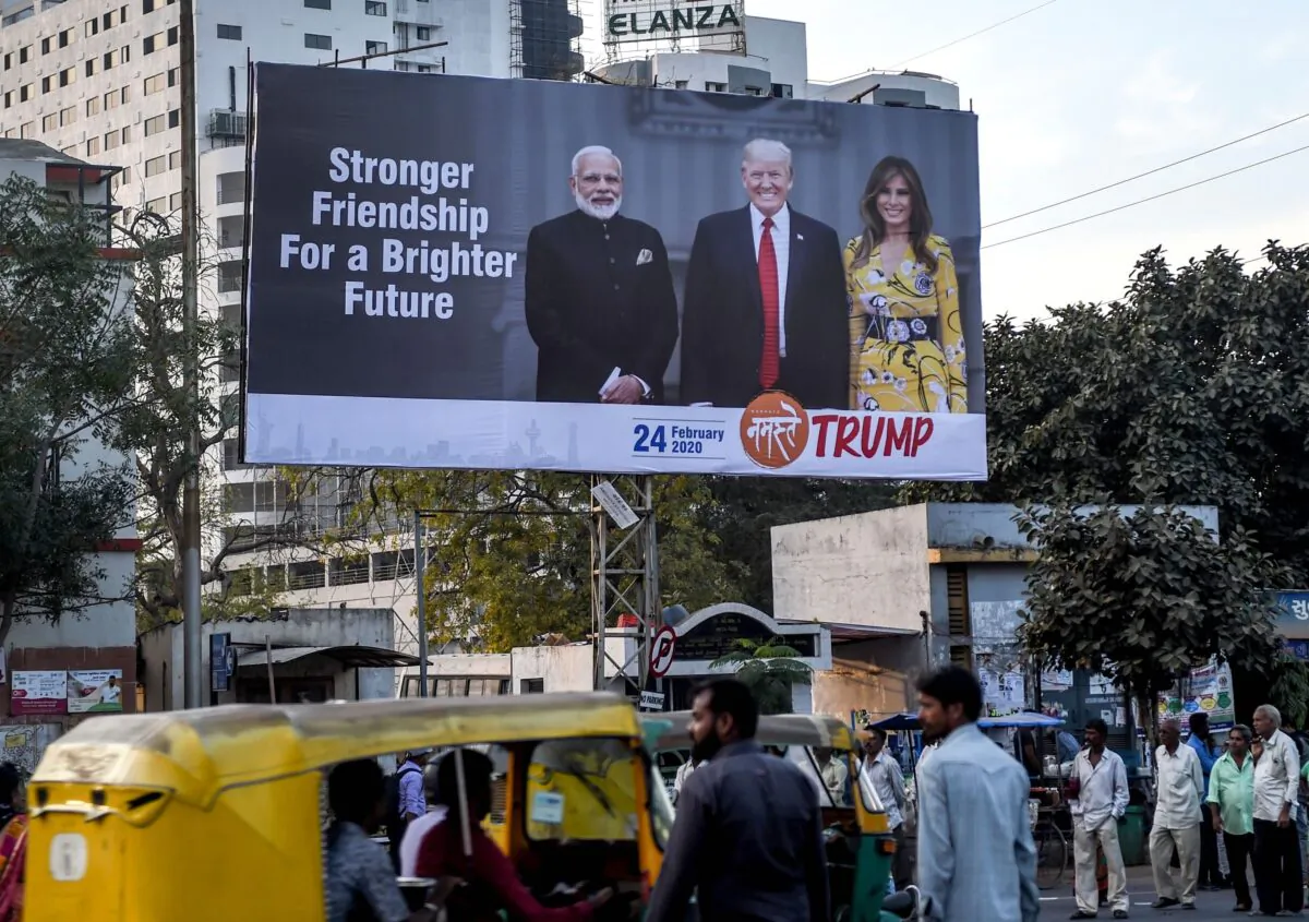 Commuters and pedestrians pass below a billboard depicting U.S. President Donald Trump (C), his wife Melania Trump (R) and India's Prime Minister Narendra Modi (L), in Ahmedabad, India, on Feb. 18, 2020. (Sam Panthaky/AFP via Getty Images)