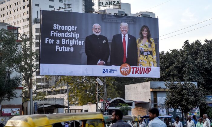 Commuters and pedestrians pass below a billboard depicting U.S. President Donald Trump (C), his wife Melania Trump (R) and India's Prime Minister Narendra Modi (L), in Ahmedabad, India, on Feb. 18, 2020. (Sam Panthaky/AFP via Getty Images)