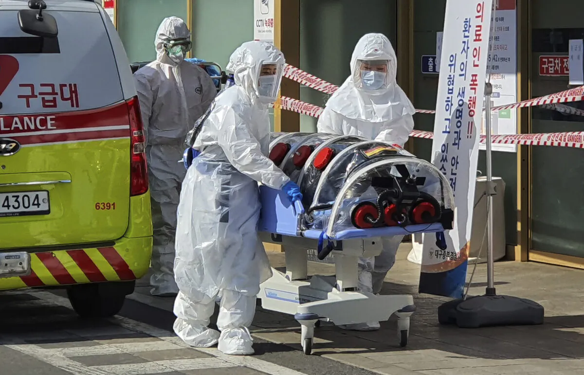 Medical workers move a patient suspected of contracting the new coronavirus from an ambulance to the Kyungpook National University Hospital in Daegu, South Korea, on Feb. 19, 2020. (Kim Jong-un/Yonhap via AP)