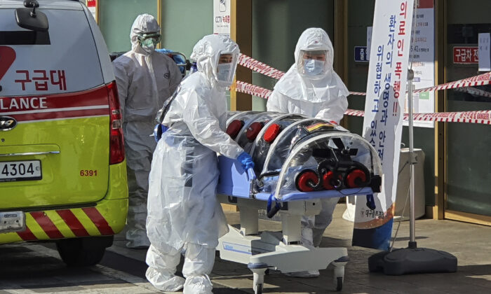 Medical workers move a patient suspected of contracting the new coronavirus from an ambulance to the Kyungpook National University Hospital in Daegu, South Korea, on Feb. 19, 2020. (Kim Jong-un/Yonhap via AP)