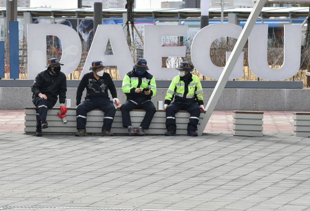 People wearing face masks sit in front of Dongdaegu railway station in the southeastern city of Daegu, South Korea, on Feb. 24, 2020. (Jung Yeon-je/AFP via Getty Images)