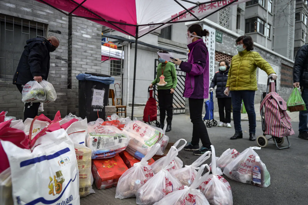Residents wearing protective face masks collect foods distributed by volunteers outside their home in Wuhan in central China's Hubei Province, on Feb. 22, 2020. (Chinatopix via AP)