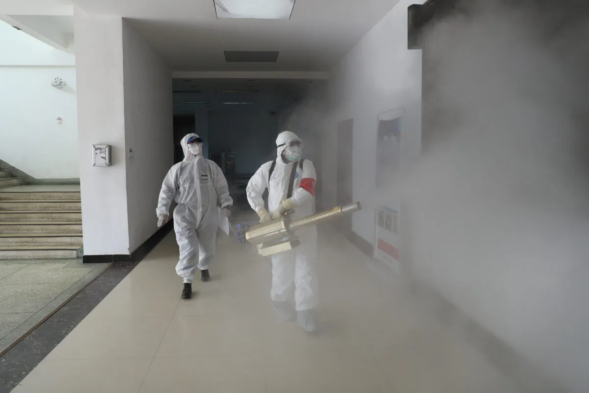 Volunteers in protective suits disinfect a residential compound in Wuhan, the epicenter of the Covid-19 outbreak, in Hubei Province in China on Feb. 22, 2020. (China Daily via Reuters)