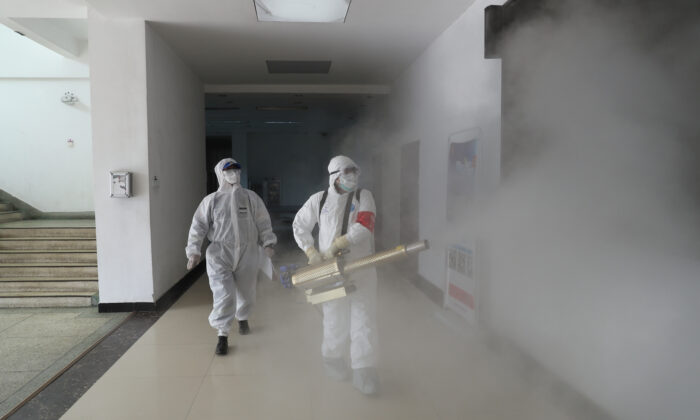 Volunteers in protective suits disinfect a residential compound in Wuhan, the epicenter of the Covid-19 outbreak, in Hubei Province in China on Feb. 22, 2020. (China Daily via Reuters)