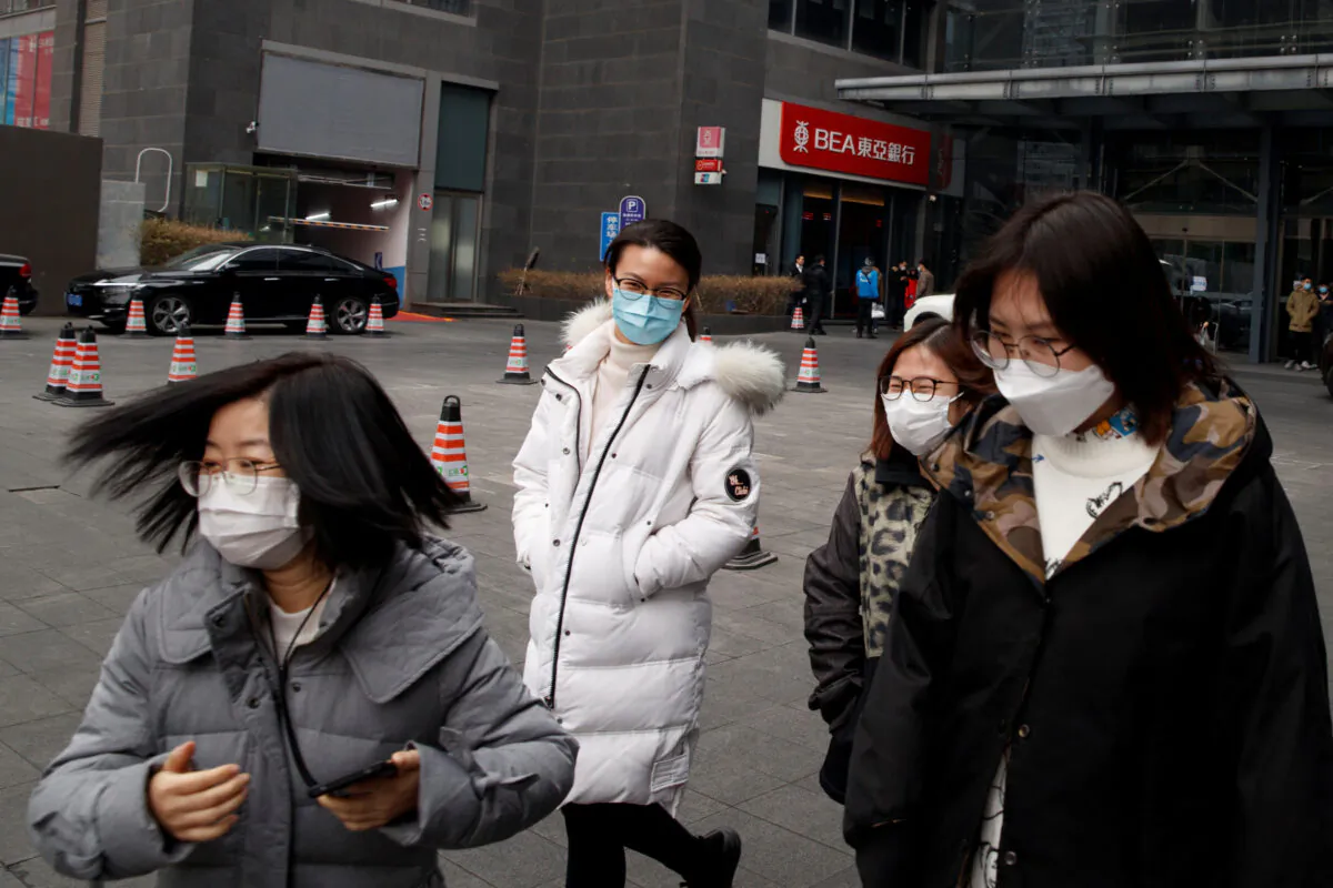 People wear face masks as they leave an office building in the Central Business District in Beijing as the country is hit by an outbreak of the novel coronavirus, China on Feb. 24, 2020. (Thomas Peter/Reuters)