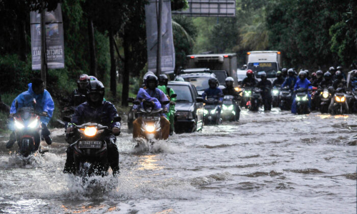 People ride motorcycles along a flooded street in Bekasi, near Jakarta, Indonesia, on Feb. 25, 2020. (Antara Foto/Fahkri Hermansyah/ via Reuters)