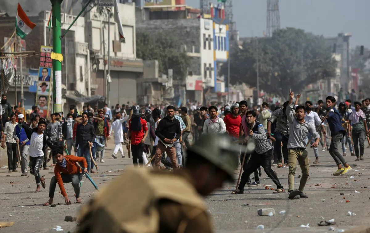 Demonstrators opposing a new citizenship law throw pieces of bricks toward riot police and those supporting the law, during a clash in New Delhi, India, on Feb. 24, 2020. (Danish Siddiqui/Reuters)