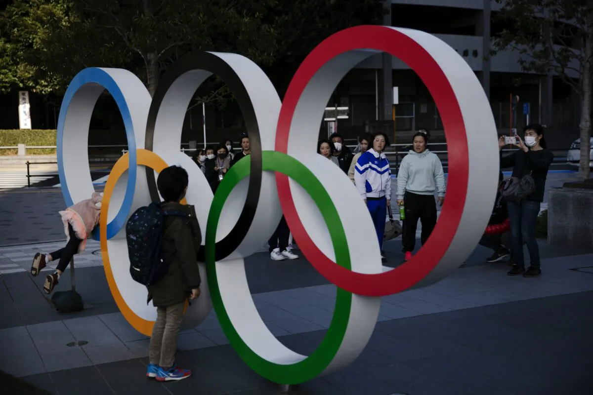 People wait in line to take pictures with the Olympic rings near the New National Stadium in Tokyo, Japan, on Feb. 23, 2020. (Jae C. Hong/AP Photo)