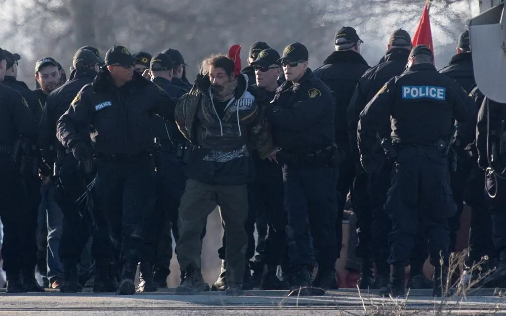 Ontario Provincial Police officers make arrests at a rail blockade in Tyendinaga Mohawk Territory, near Belleville, Ont., on Feb. 24, 2020, as they protest in solidarity with Wet'suwet'en Nation hereditary chiefs attempting to halt construction of a natural gas pipeline on their traditional territories. (The Canadian Press/Adrian Wyld)