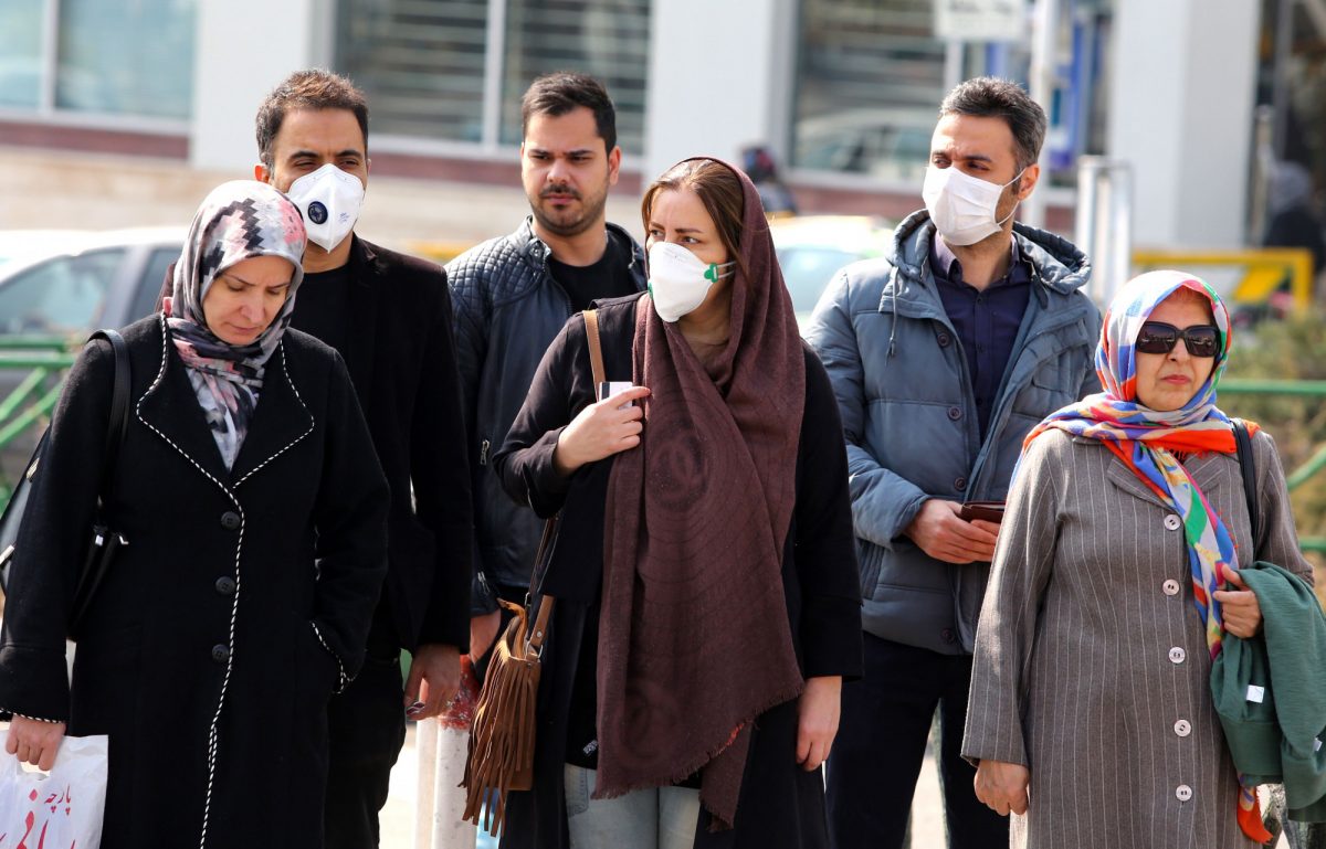 Iranians, some wearing protective masks