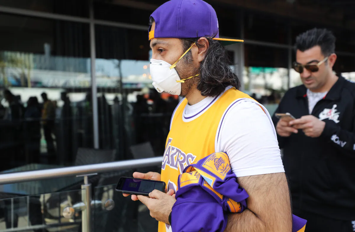 A fan wears a protective mask as people wait in line to attend the ‘Celebration of Life for Kobe and Gianna Bryant’ memorial service at Staples Center in Los Angeles on Feb. 24, 2020. (Mario Tama/Getty Images)