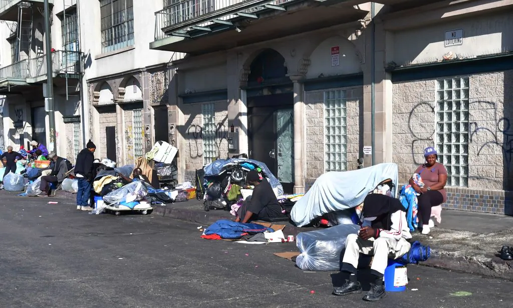 Homeless men and women sit out on a sidewalk in Los Angeles, on Jan. 8, 2020. (Frederic J. Brown/AFP via Getty Images)