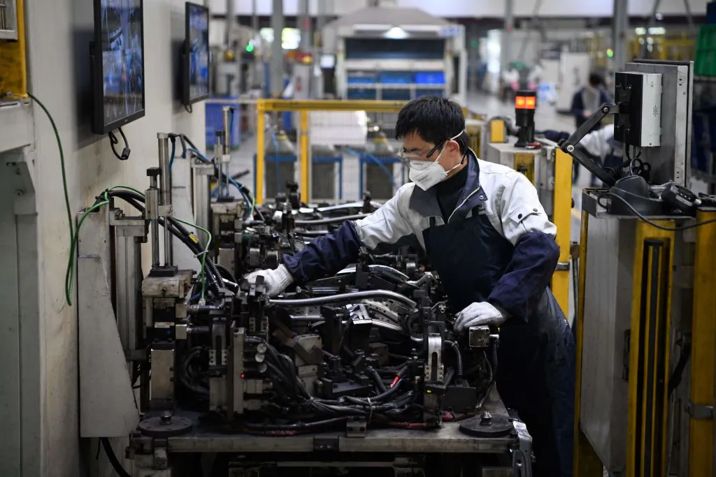 A worker wearing a protective face mask works on a car seat assembly line at Yanfeng Adient factory in Shanghai on Feb. 24, 2020. (Noel Celis/AFP via Getty Images)