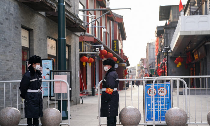 Security guards wear protective masks as they stand on a nearly empty commercial street in Beijing on Feb. 25, 2020. (Lintao Zhang/Getty Images)