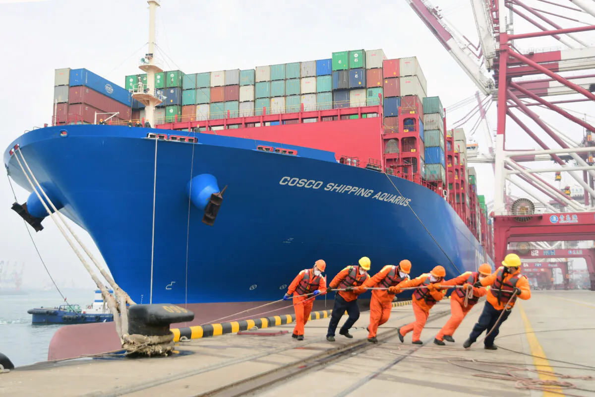 Workers wearing face masks rope a container ship at a port in Qingdao, Shandong Province, China on Feb. 11, 2020. (China Daily via Reuters)