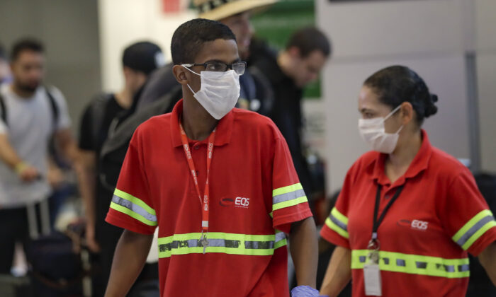 Airport employees wear masks as a precaution against the spread of the new coronavirus COVID-19 as they work at the Sao Paulo International Airport in Sao Paulo, Brazil on Feb. 26, 2020. (Andre Penner/AP Photo)